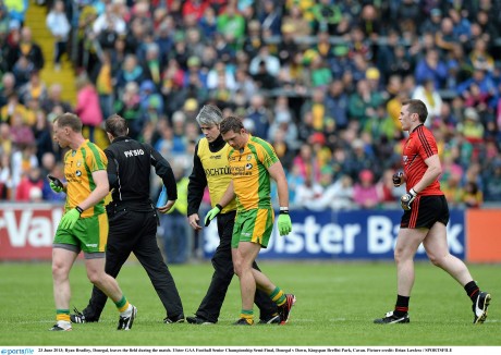 Ryan Bradley, Donegal, leaves the field during the 2013 Ulster semi-final against Down. Dr Charlie McManus is accompanying the player.