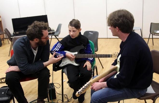 Ruairi Friel and Charlie Doherty with guitar pupil Reelan McHugh. Photos: Donna El Assaad