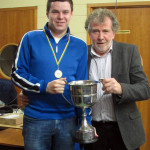 Cormac Ó Colla ag bronnadh corn ar Chonor Ó Gallachóir a fuair an chad it sa Ranng Ard teistimireachta.